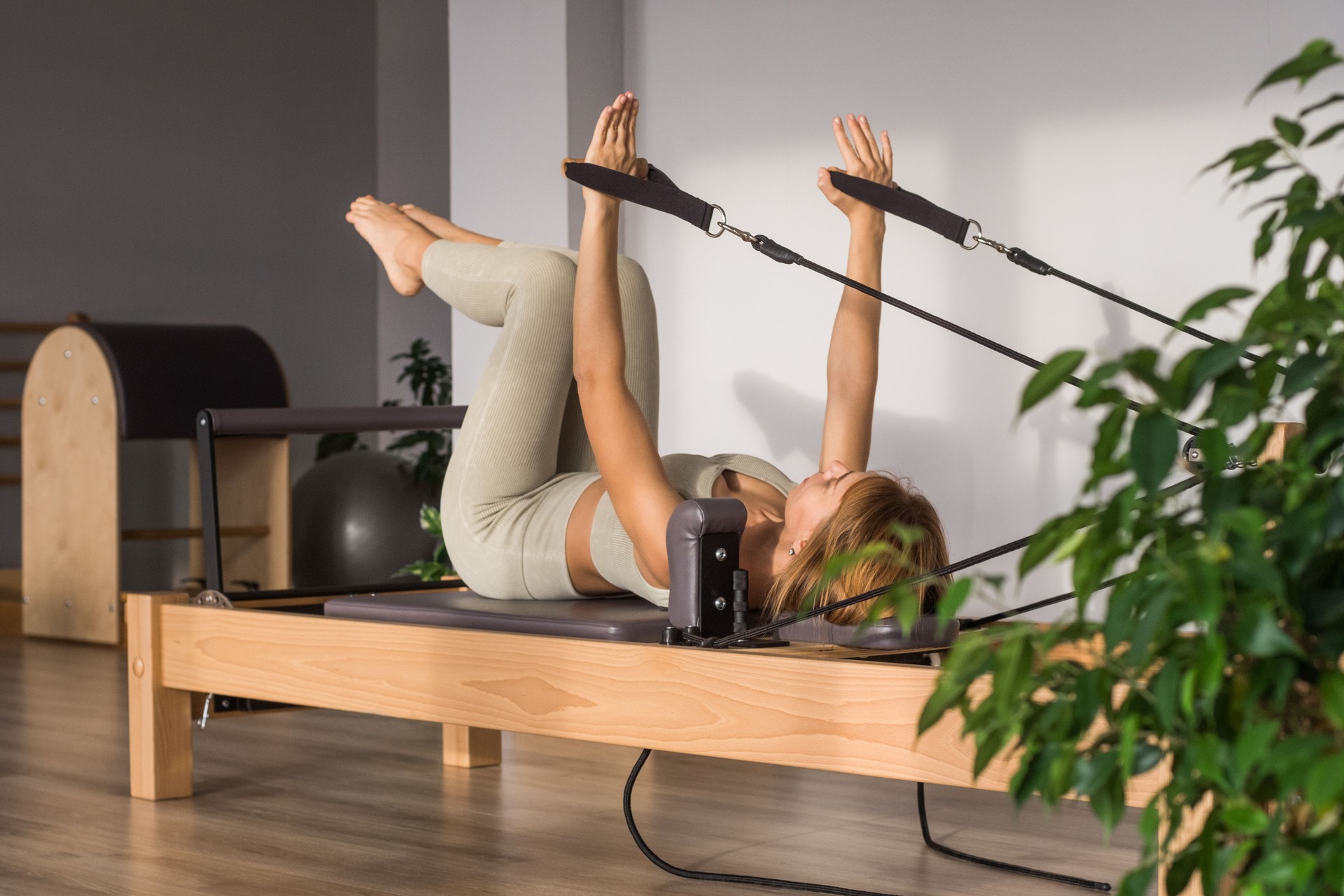 Woman training pilates on the reformer bed. Reformer pilates studio machine for fitness workouts in gym. Fit, healthy and strong authentical body. Fitness concept